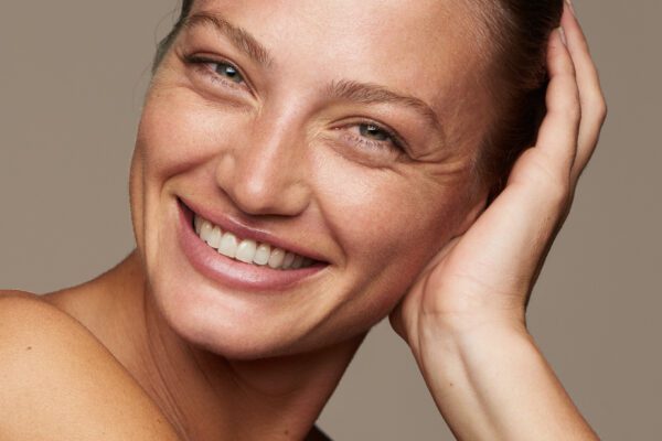 Smilende kvinde med hånden ved ansigtet og naturlig makeup